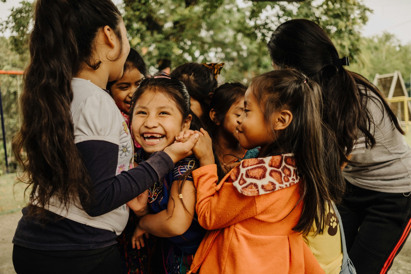 Children laughing and holding hands at a community programme