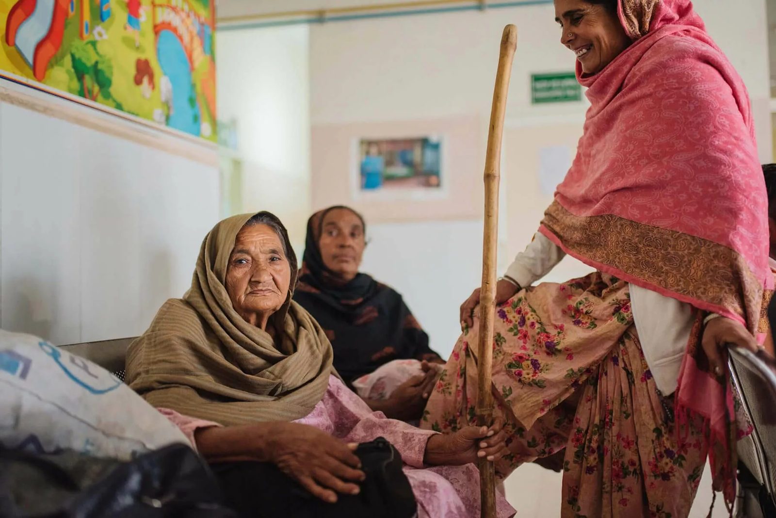 A caregiver with two older women in a clinic waiting room.