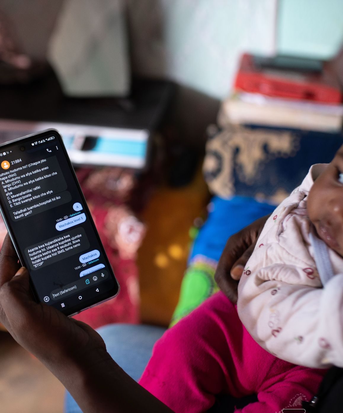 A mother holding her baby reads PROMPTS messages on her phone.